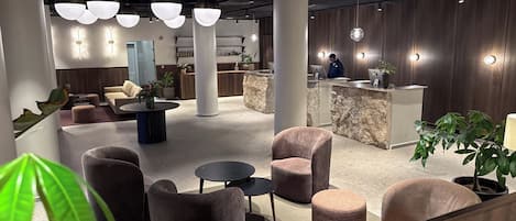 Un lobby moderno con zonas de estar, un mostrador de recepción e iluminación decorativa.