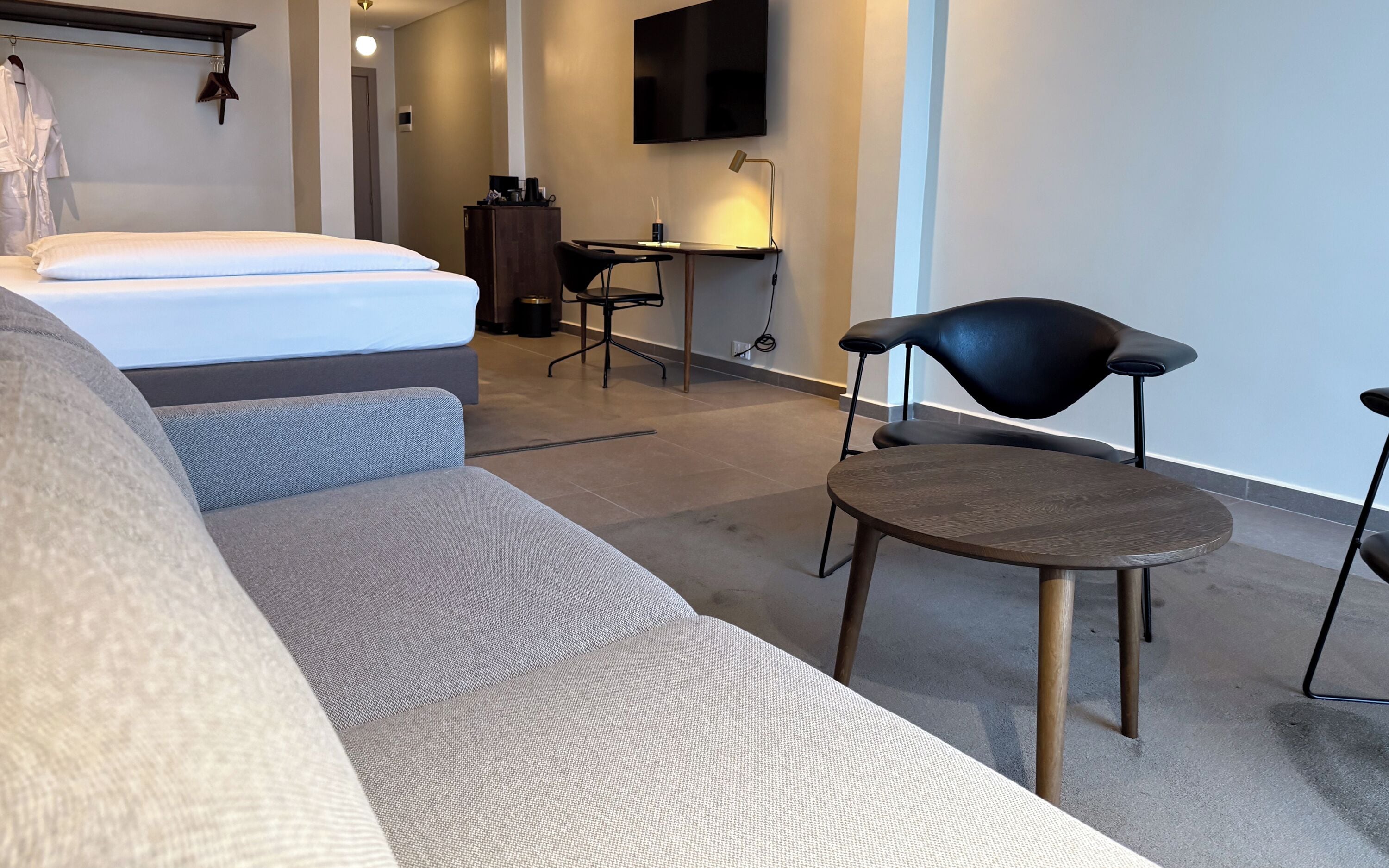 Una habitación de hotel moderna con cama, sofá, escritorio y televisor.