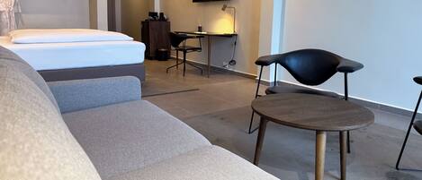 Una habitación de hotel moderna con cama, sofá, escritorio y televisor.