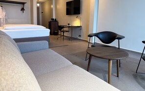 A modern hotel room with a bed, a sofa, a desk, and a TV. - The Nordic Abuja (Abuja)