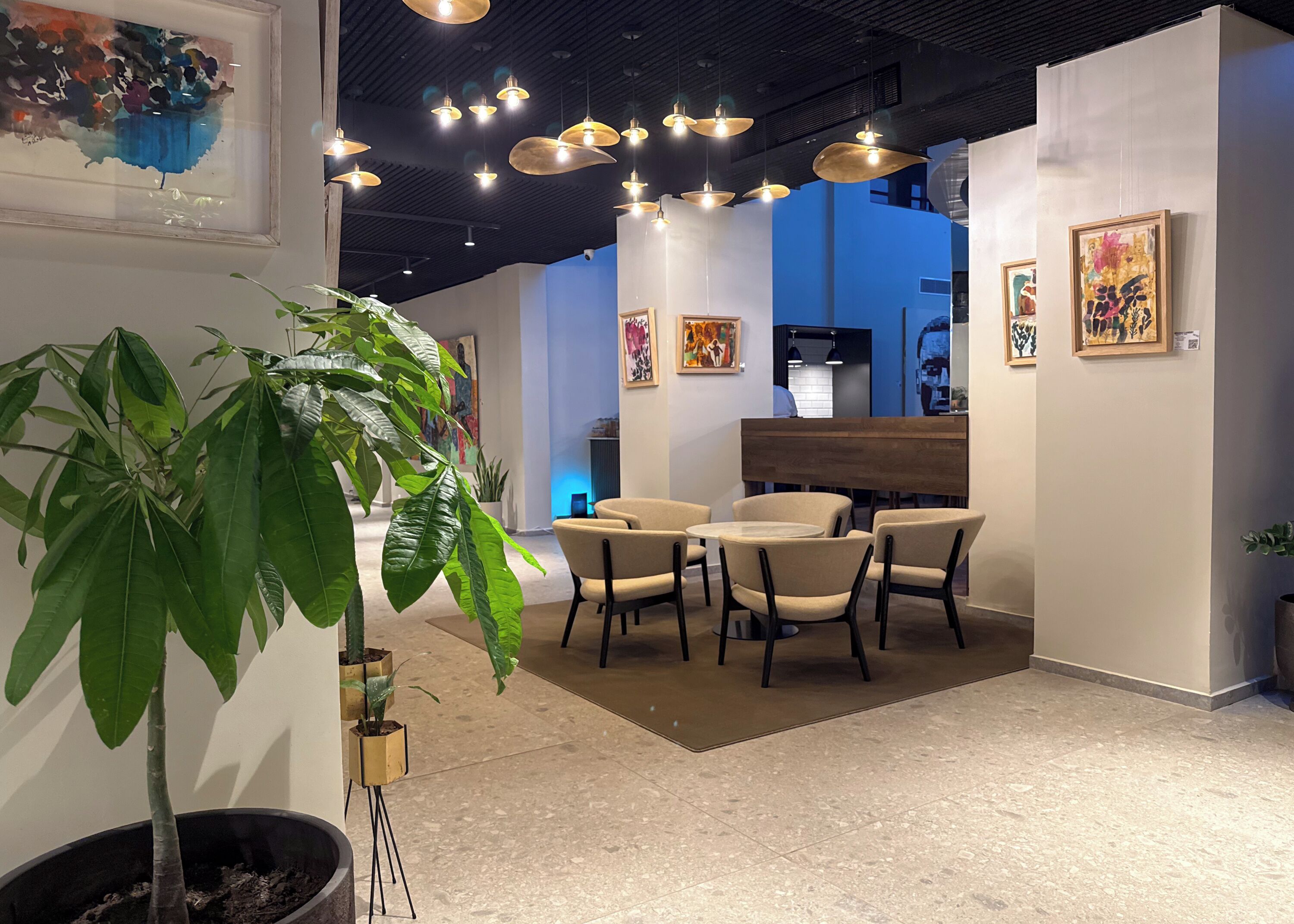 A modern interior with a seating area, artwork on the walls, and hanging pendant lights.