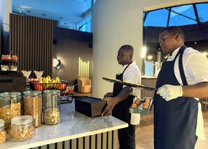 A modern kitchen with a marble countertop, various food containers, and a display of fruits and nuts. - The Nordic Abuja (Abuja)