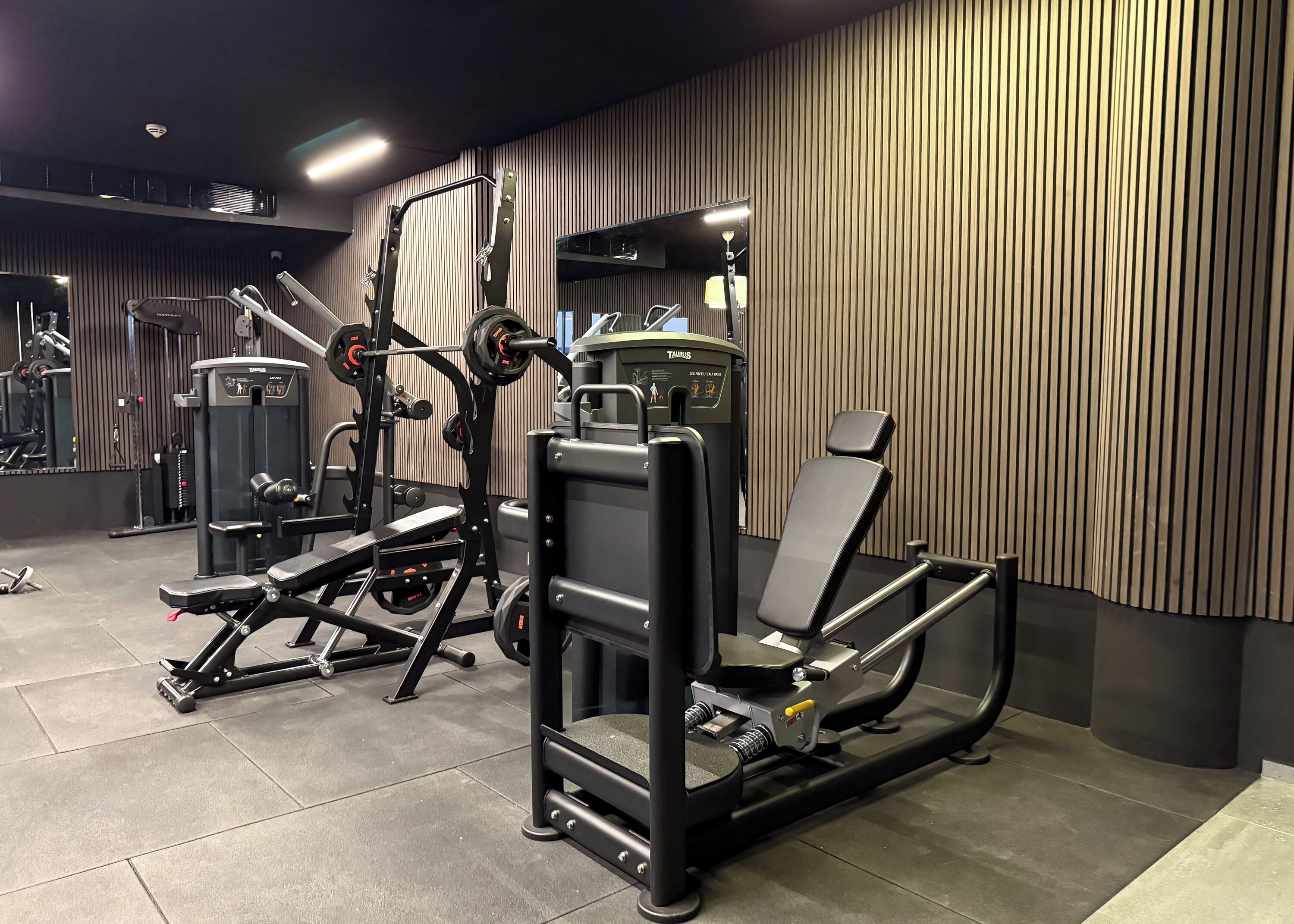 A modern gym with various exercise equipment, including a treadmill, weight machines, and a bench press.