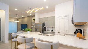 A modern kitchen with a central island, bar stools, and stainless steel appliances.