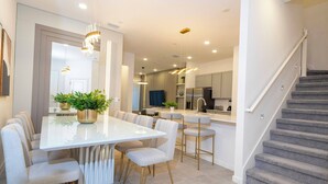 A modern kitchen with a central island, bar stools, and pendant lighting.