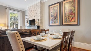 A dining area with a white table set for four, surrounded by wooden chairs. - No Car Needed+King Bed+Balcony - Abercorn and York (Savannah)