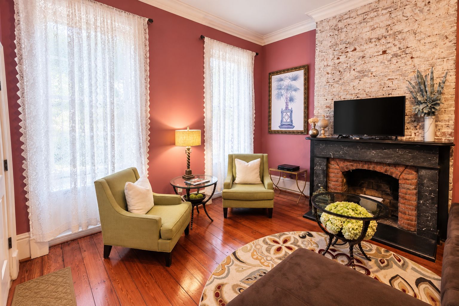 A living room with a fireplace, two armchairs, a television, and a patterned rug.