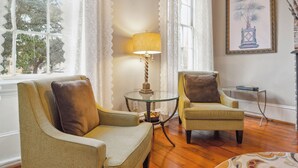 A room with two wicker armchairs, a glass table with a lamp, and a framed artwork on the wall. - No Car Needed+King Bed+Balcony - Abercorn and York (Savannah)