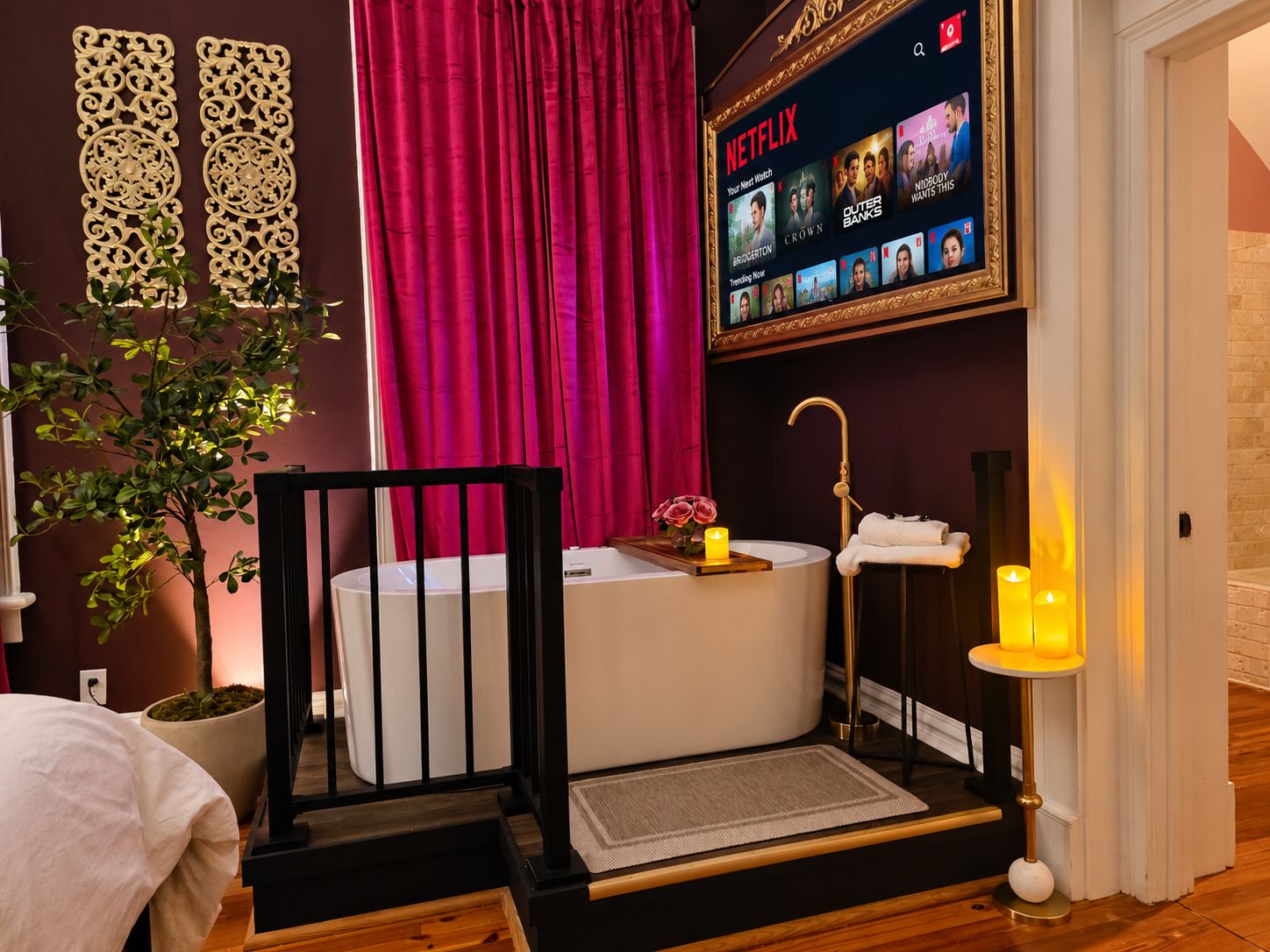 A modern bathroom with a bathtub, a vanity, and a wall-mounted Netflix display.