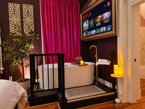 A modern bathroom with a bathtub, a vanity, and a wall-mounted Netflix display.
