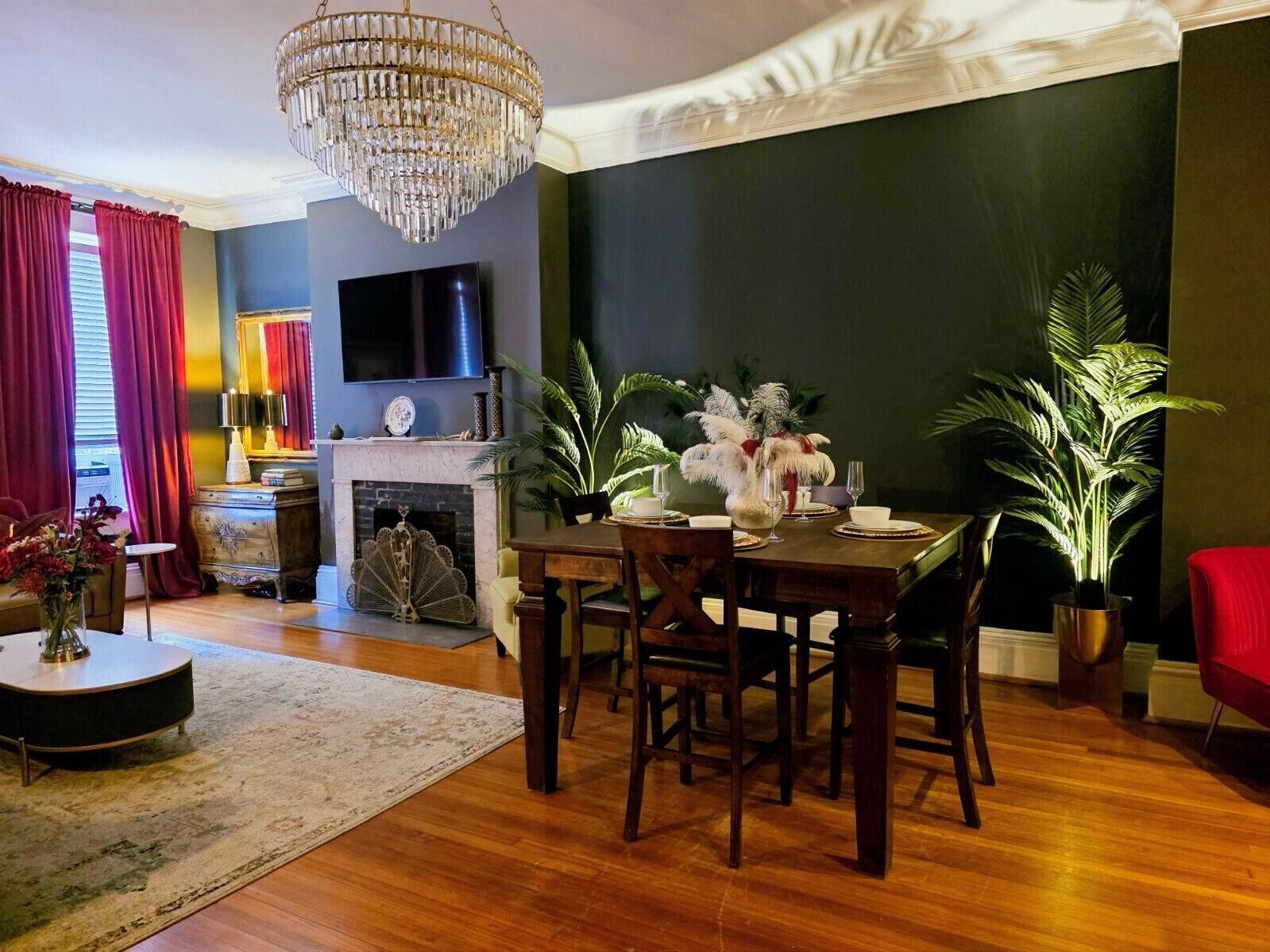 A dining area with a chandelier, a fireplace, and a television mounted on the wall.