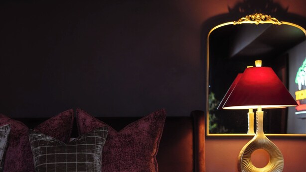 Ein Hotelzimmer mit einem Bett, Kissen, einem Nachttisch mit Lampe und einem Spiegel.