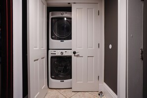 A laundry room with two stacked washing machines and a door.