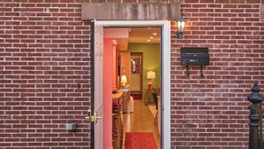A red brick building with a white door and window, a black mailbox, and a doormat. - Walk to River Street, Bars, Shopping, and Sleeps 8 (Savannah)