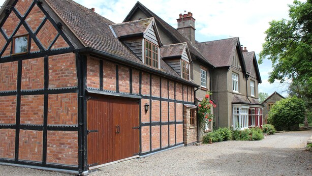 A traditional half-timbered house with a gravel driveway and a small garden.