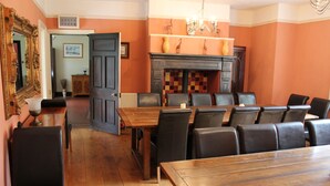 A dining area with a wooden table and black leather chairs, a fireplace with a checkered mantle, and a mirror on the wall.