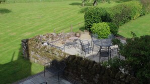 A patio with stone walls, metal chairs, and a table.