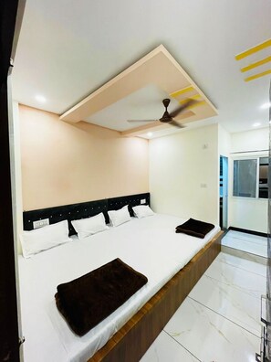 Habitación de hotel moderna con una cama grande, ventilador de techo y vistas al exterior.