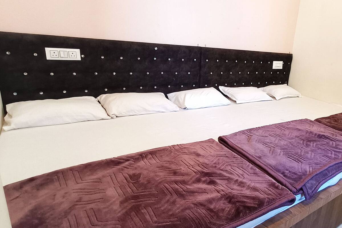Una cama con cabecera, almohadas blancas y una colcha púrpura.