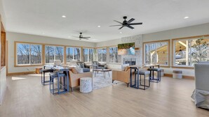 A spacious living room with large windows, a fireplace, and ceiling fans. - Spacious Getaway for 22 w/ Pool, Hot Tub & Huge Game Room – Perfect for Groups! (Logan)