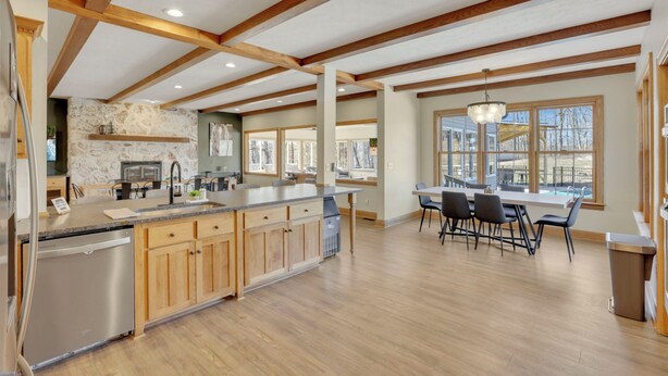 A spacious kitchen with wooden beams, a central island, and a dining area with a view. - Spacious Getaway for 22 w/ Pool, Hot Tub & Huge Game Room – Perfect for Groups! (Logan)