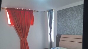 A bedroom with a bed, a window with curtains, a headboard, and a ceiling light. - Hotel Paraiso Real (Cumbal)