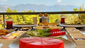 A table with various dishes and a watermelon centerpiece, set against a scenic mountain backdrop.