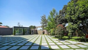 Un vaste espace extérieur doté d’une terrasse en pierre à motifs et d’une pelouse artificielle verdoyante.