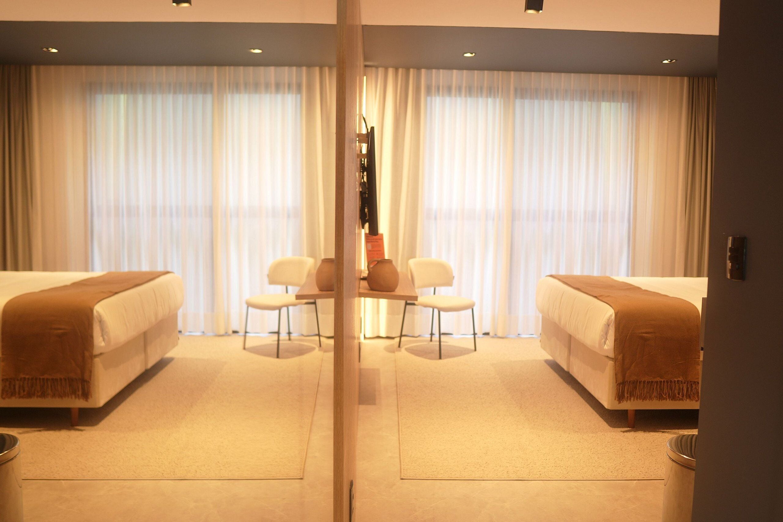Een hotelkamer met twee bedden, een bureau en stoelen.