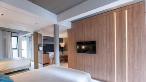 Una camera d'albergo moderna con un letto grande, una TV fissata al muro e un pannello decorativo in legno.
