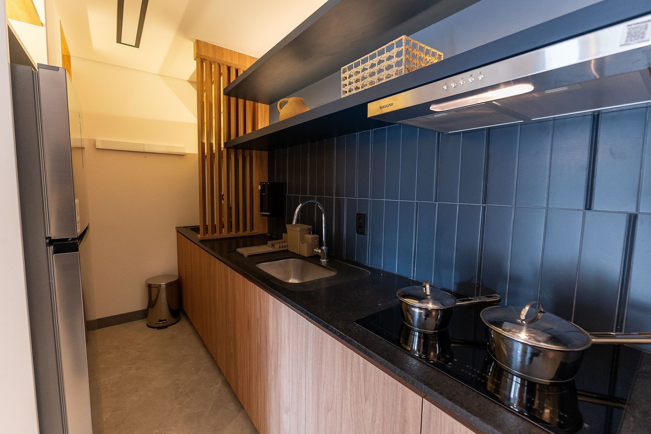 A modern kitchen with a black countertop, stainless steel appliances, and blue-tiled backsplash.