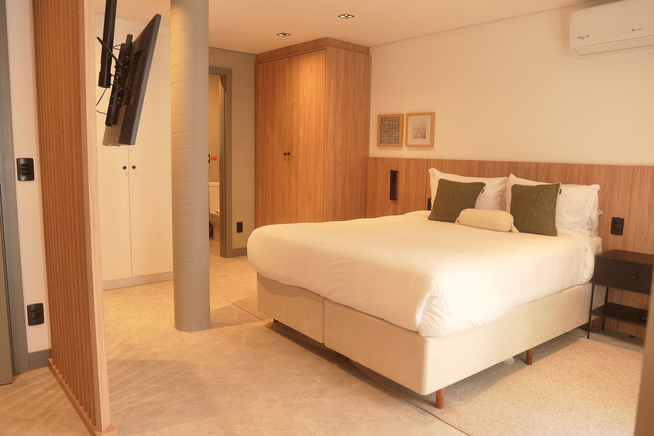 Ein modernes Schlafzimmer mit einem großen Bett, einem Kleiderschrank und einem an der Wand montierten Fernseher.
