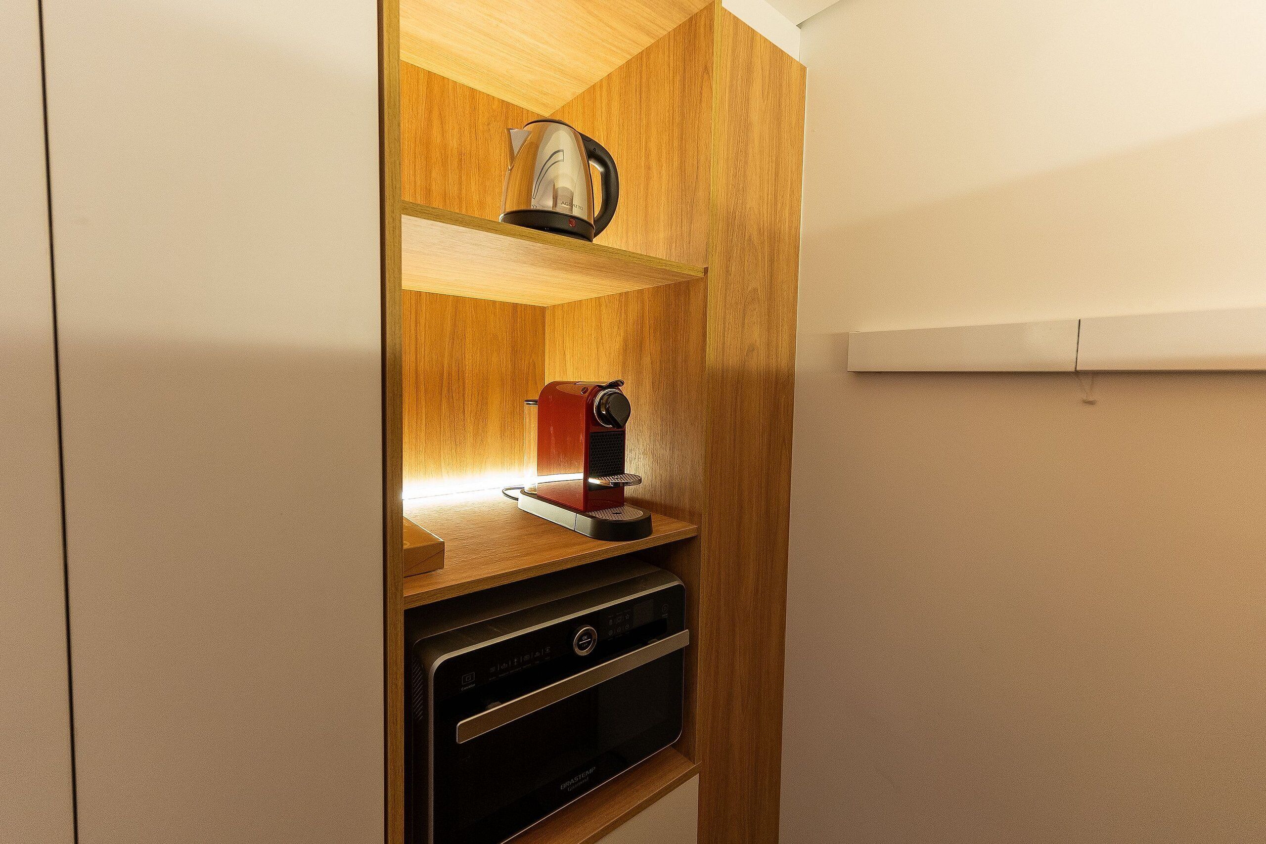 A compact kitchen with a coffee maker, kettle, and oven.