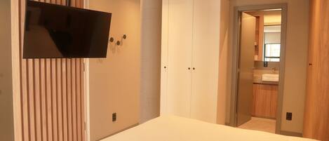 Una camera da letto moderna con un letto grande, una TV a parete e un cabina armadio.