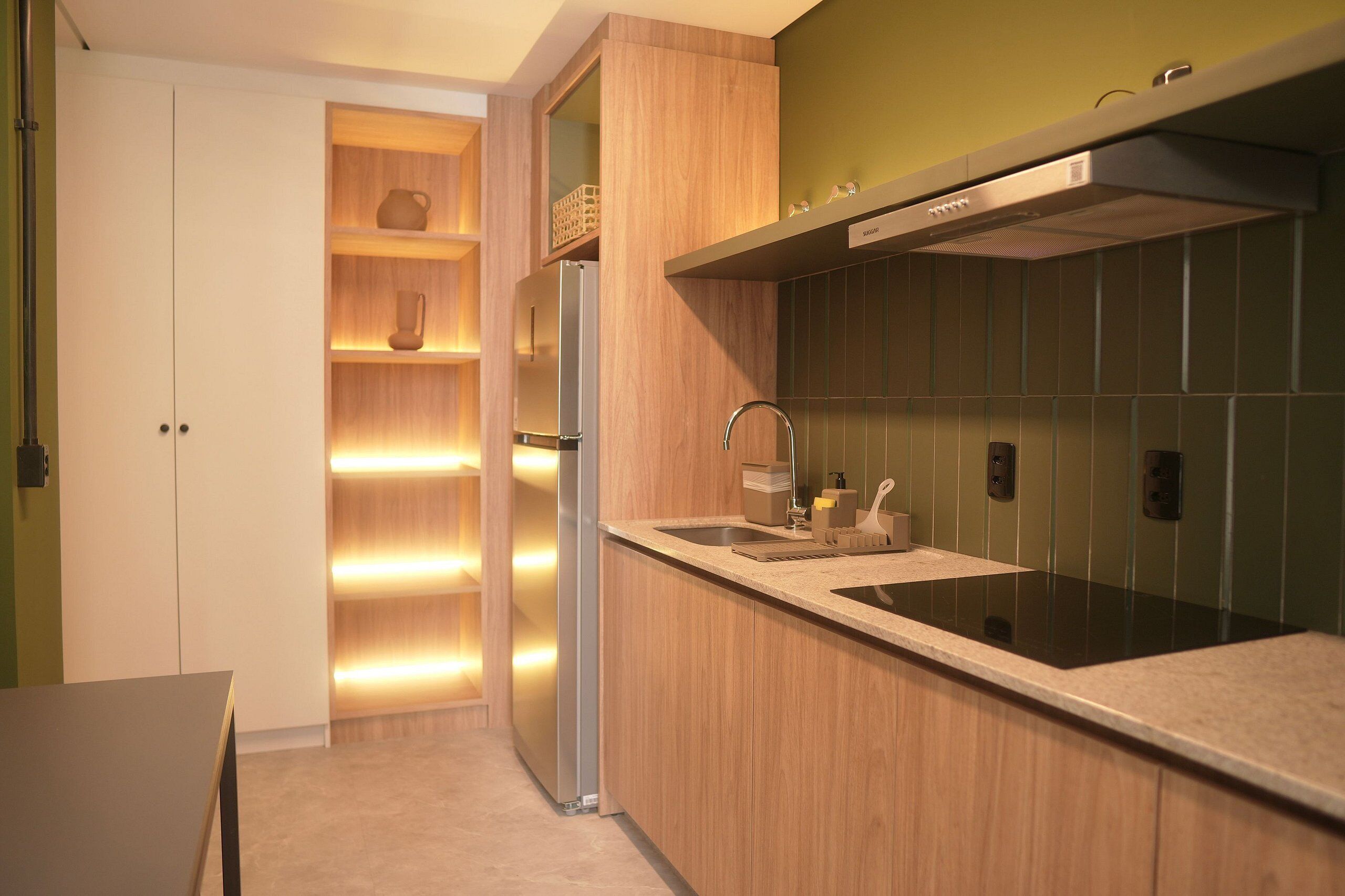 A modern kitchen with wooden cabinets, a stainless steel refrigerator, and a black countertop.