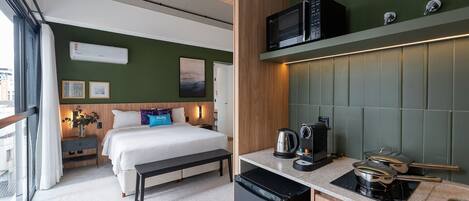 Ein modernes Hotelzimmer mit Bett, Nachttisch und einer Küchenzeile mit Mikrowelle und Wasserkocher.