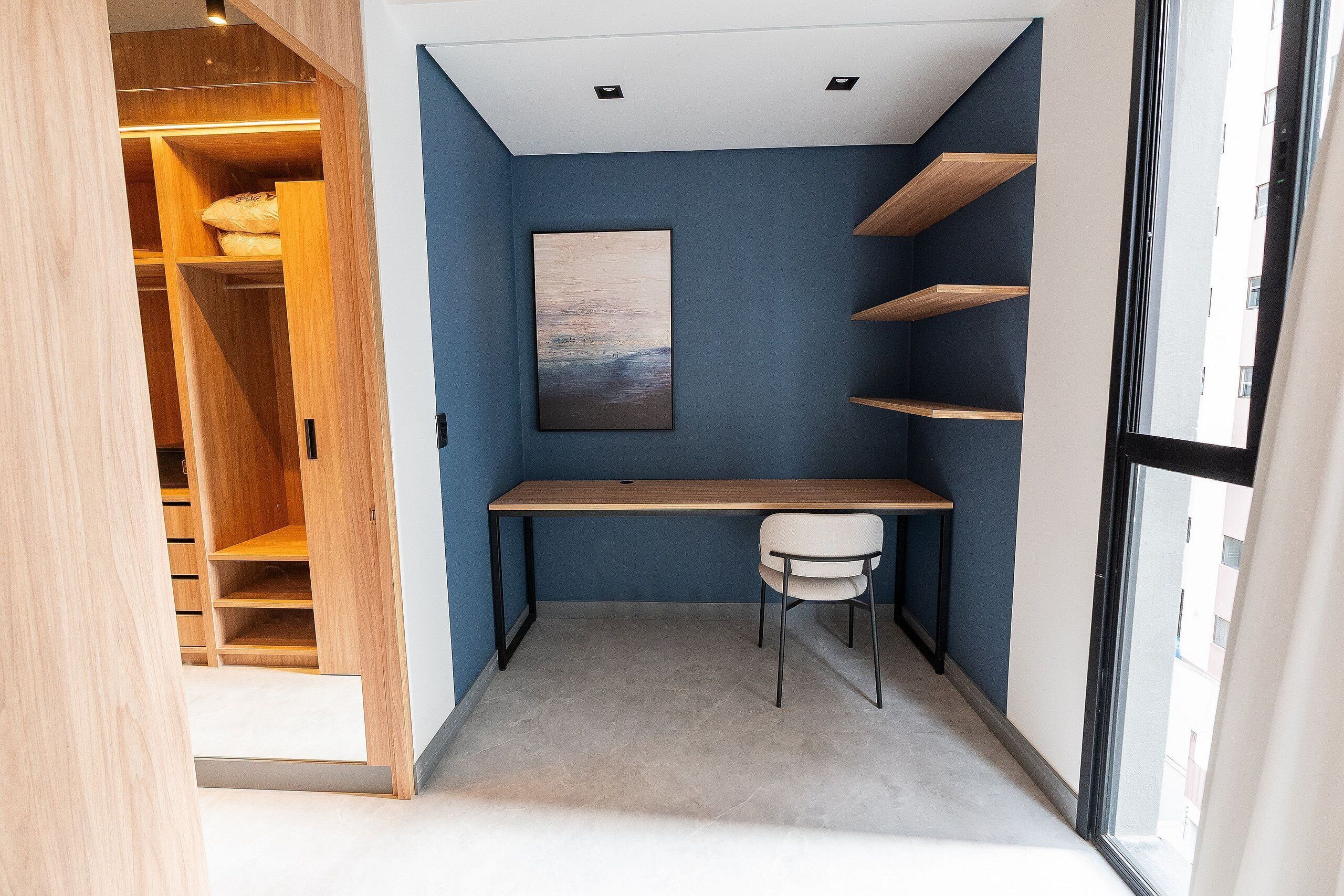 A compact room with a desk, chair, and built-in shelving.
