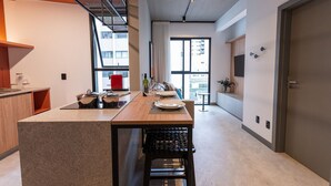 Una cucina moderna con isola centrale, zona pranzo con tavolo e sedie, e ampie finestre vista città.