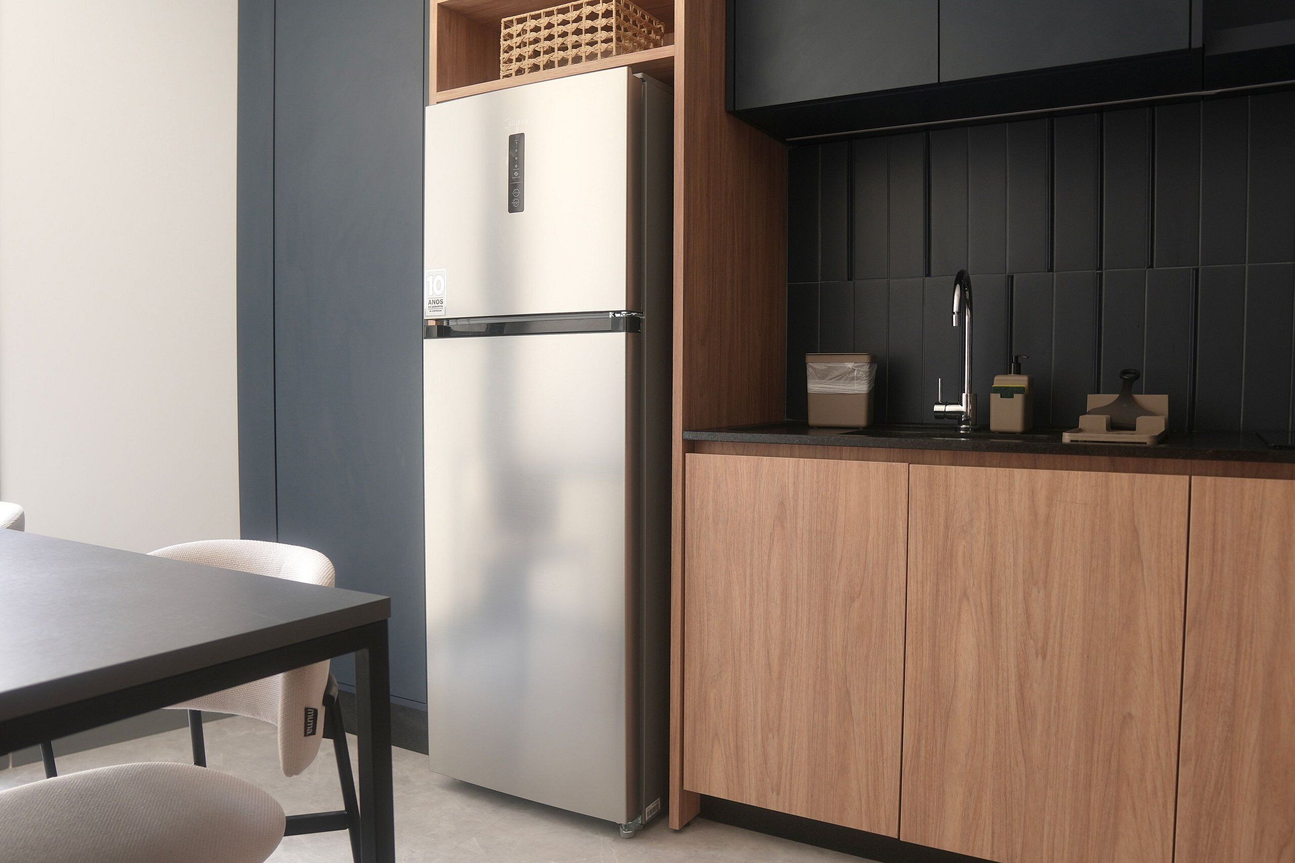 A modern kitchen with a built-in refrigerator, wooden cabinets, and a dark backsplash.