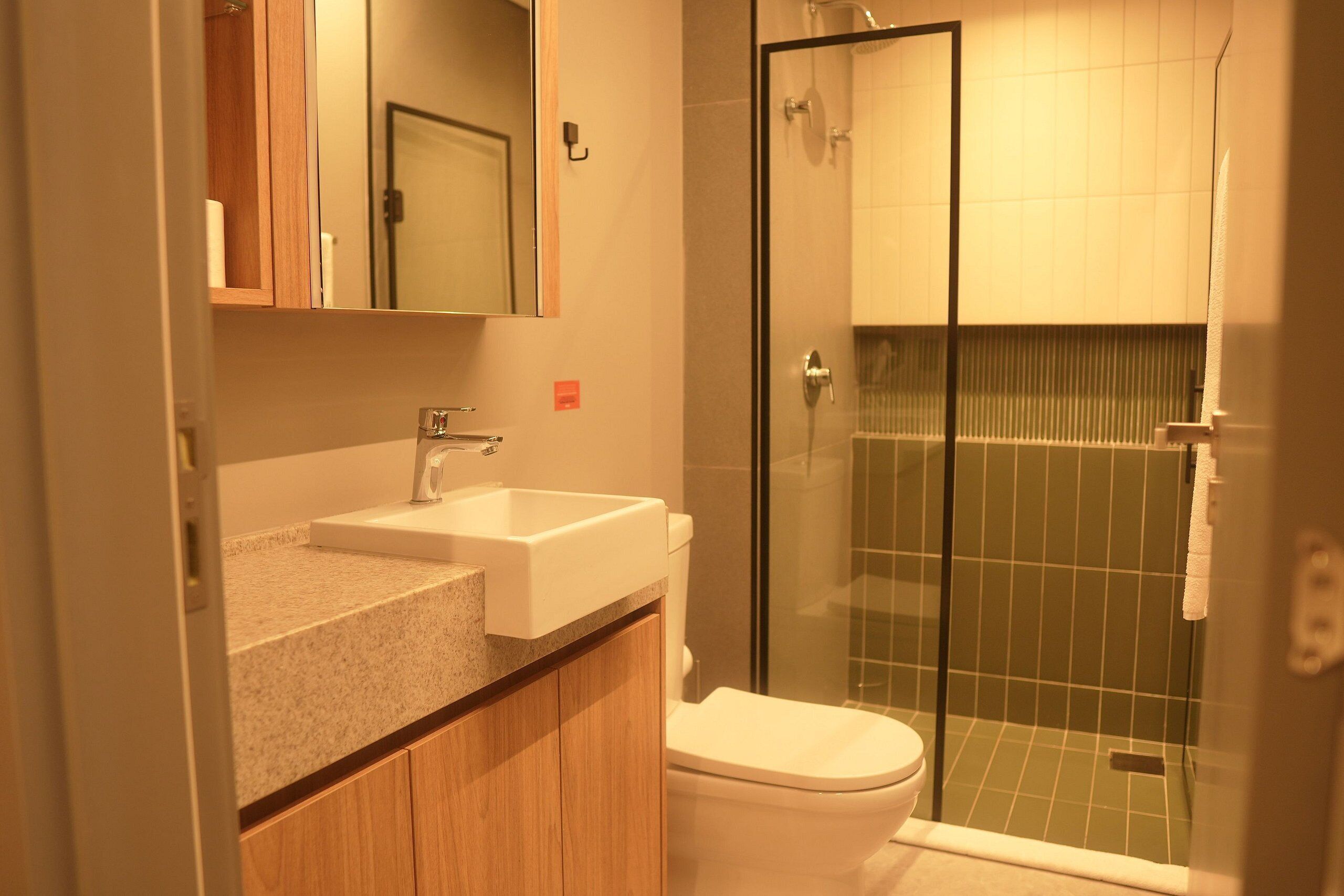 A bathroom with a sink, toilet, and glass shower enclosure.