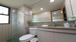A bathroom with a toilet, a glass shower enclosure, a sink with a granite countertop, and a mirror above the sink. - Malawi Beach Resort (Ipojuca)