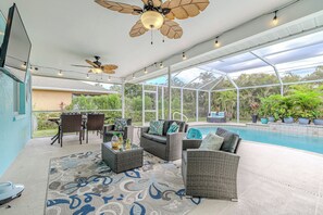 A covered outdoor patio with wicker furniture, a pool, and a ceiling fan.