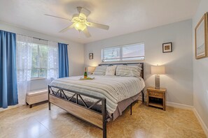 A bedroom with a bed, bedside lamps, a ceiling fan, and a window with curtains.