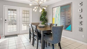 A dining area with a chandelier, a map on the wall, and a door with frosted glass panels.