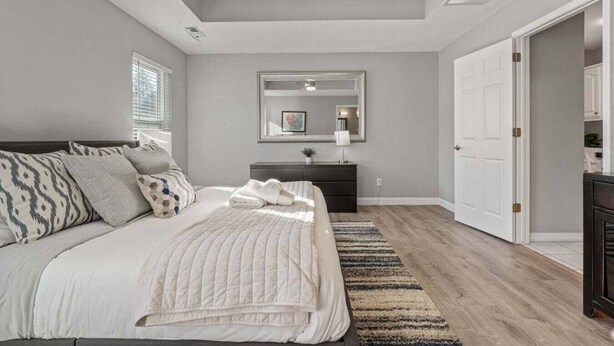 A bedroom with a bed, a dresser, a mirror, and a ceiling fan.
