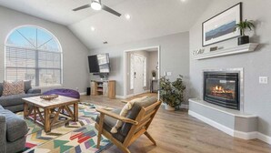 A living room with a fireplace, a TV, and a ceiling fan.
