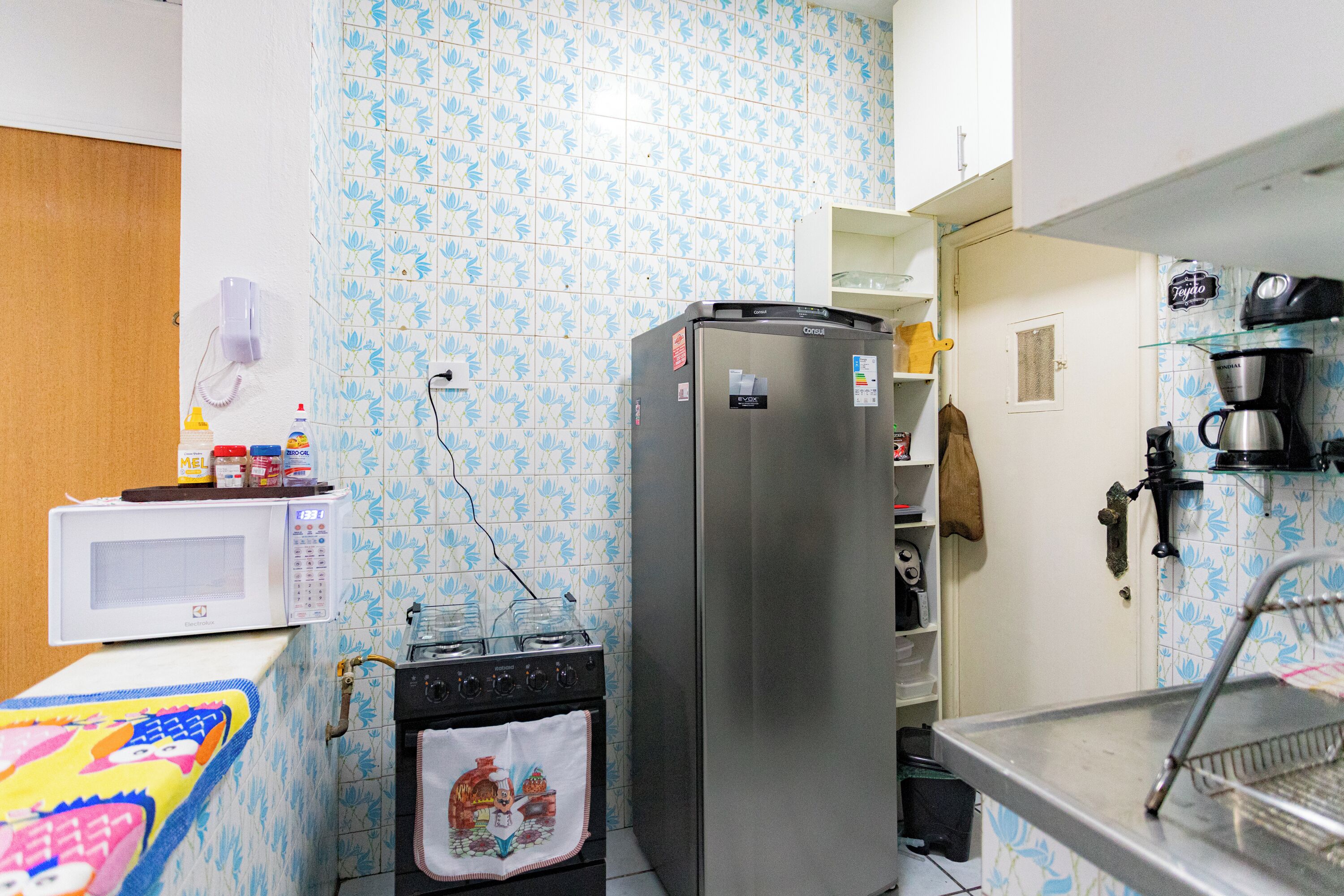 A compact kitchen with a microwave, stove, refrigerator, and a coffee maker.