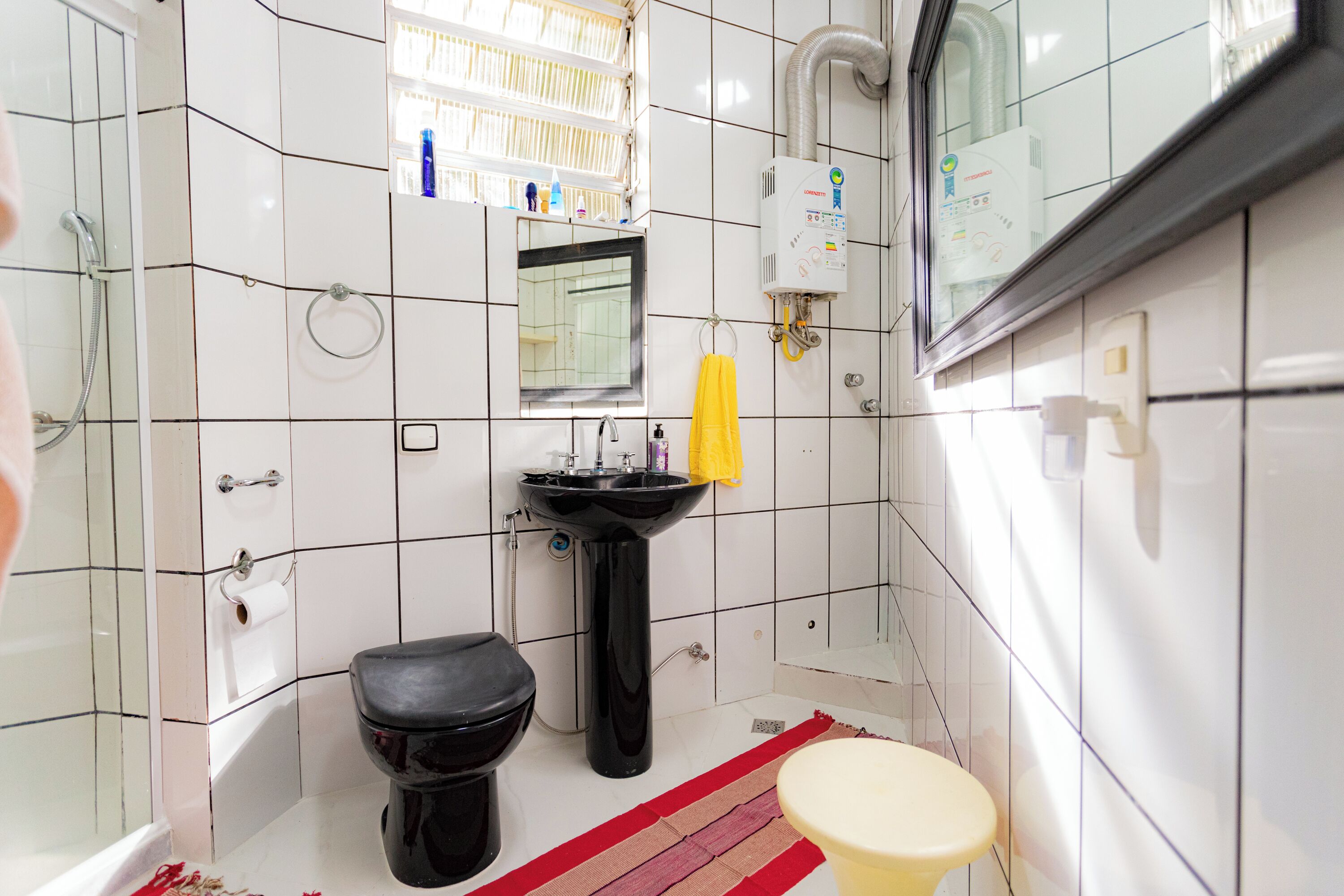 A bathroom with a black toilet, a sink, a bathtub, and a mirror.