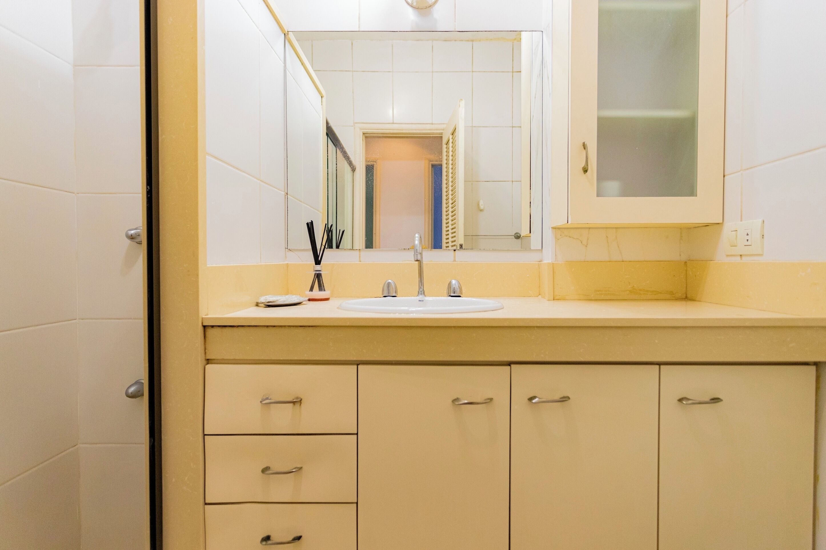Une salle de bain avec un lavabo, un miroir et des placards.