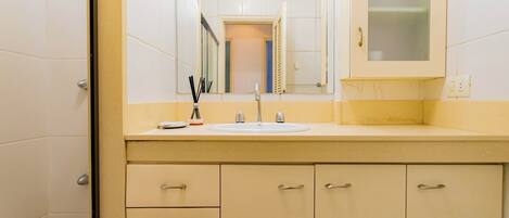 Une salle de bain avec un lavabo, un miroir et des placards.